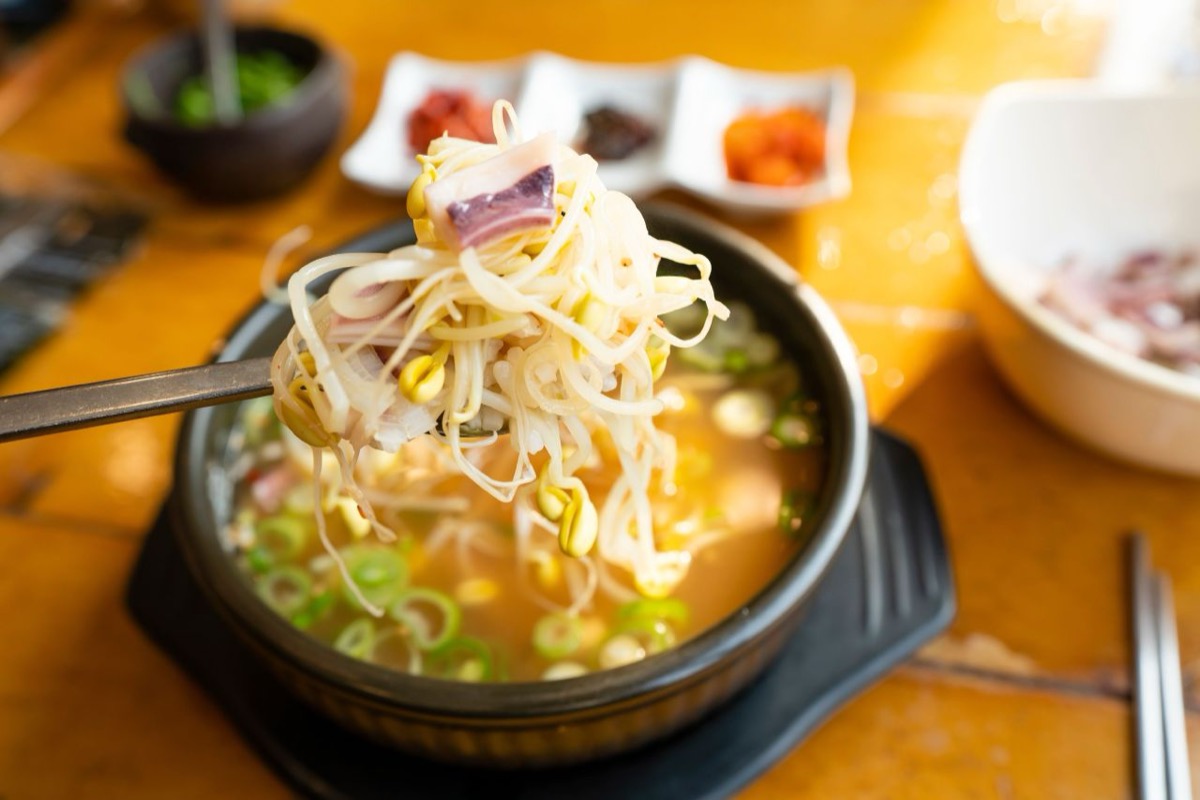 A bowl of bean sprout soup with side dishes